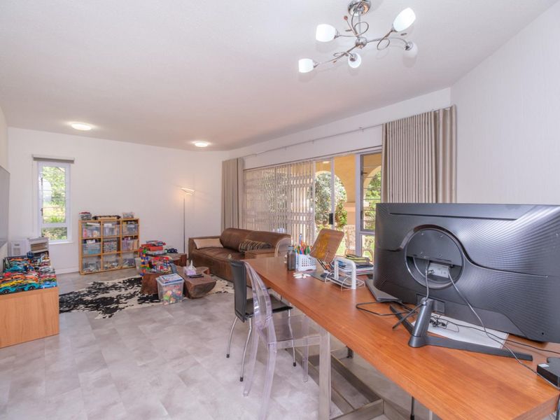 Spacious living area featuring tiled flooring, modern lighting, and large sliding glass doors that provide access to the outdoor patio area.