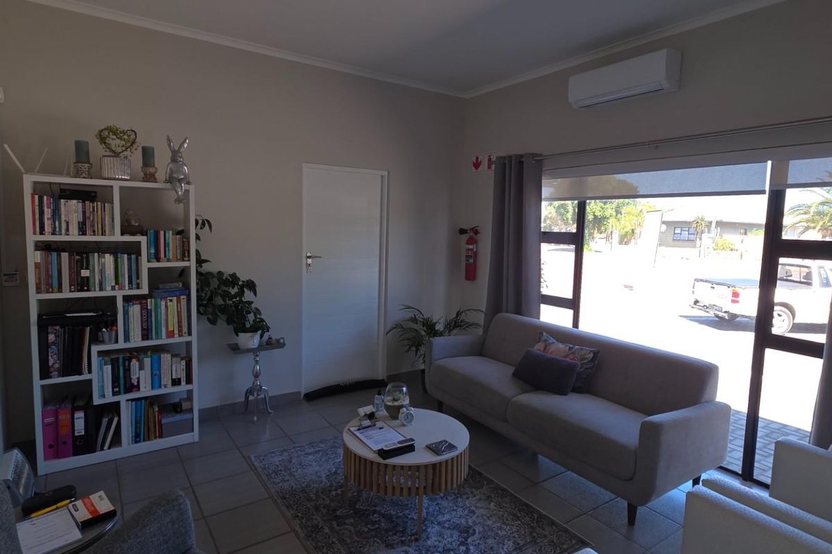 A well-maintained commercial office or reception area featuring tiled flooring, a split-system air conditioner, and large glass doors providing natural light.