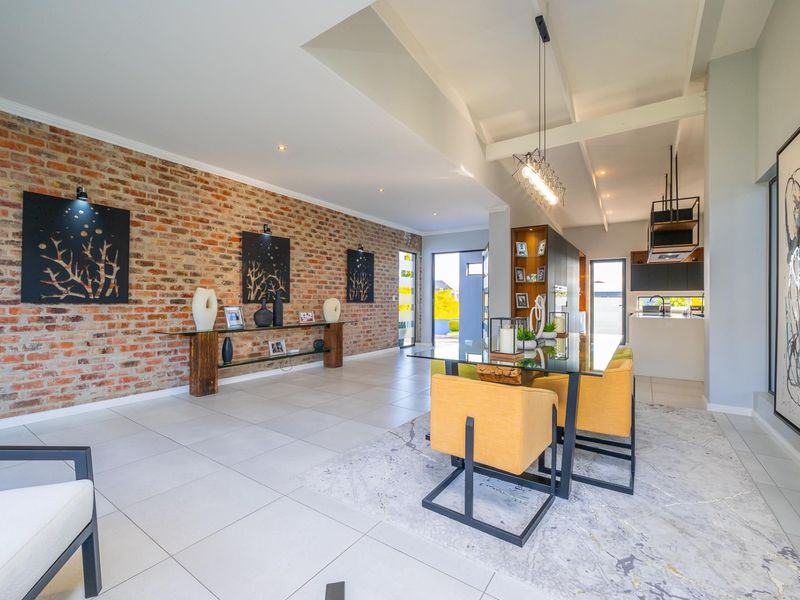 Spacious open-plan living and dining area featuring an exposed brick feature wall, modern tiled flooring, and a seamless transition to a contemporary kitchen.
