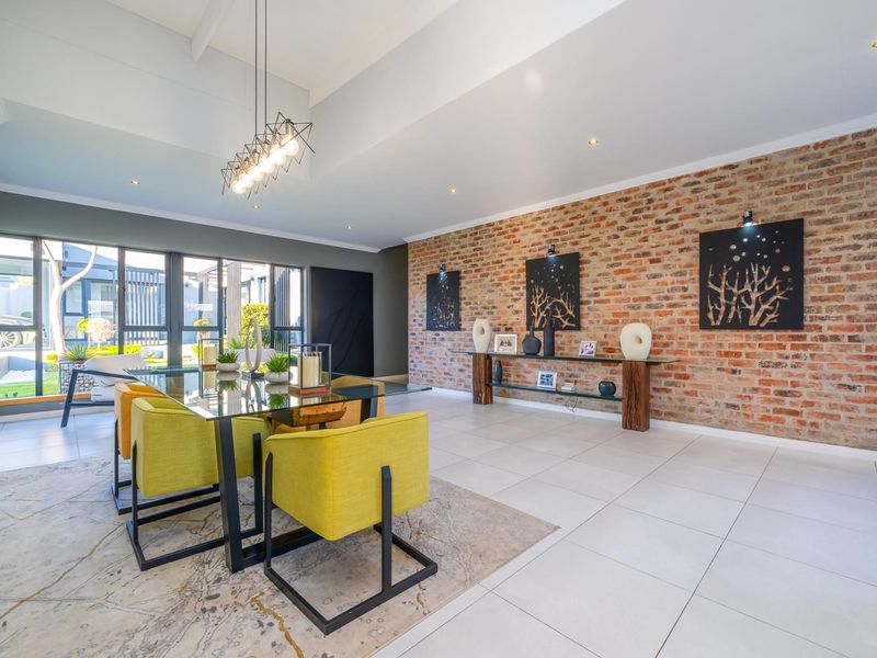 Spacious dining area featuring a striking exposed brick feature wall, vaulted ceilings, large windows, and modern tiled flooring.
