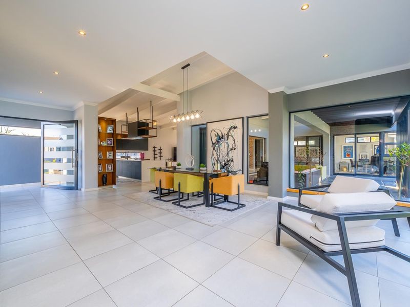 Spacious open-plan living and dining area featuring vaulted ceilings, modern tiled flooring, and large glass doors providing seamless indoor-outdoor flow.