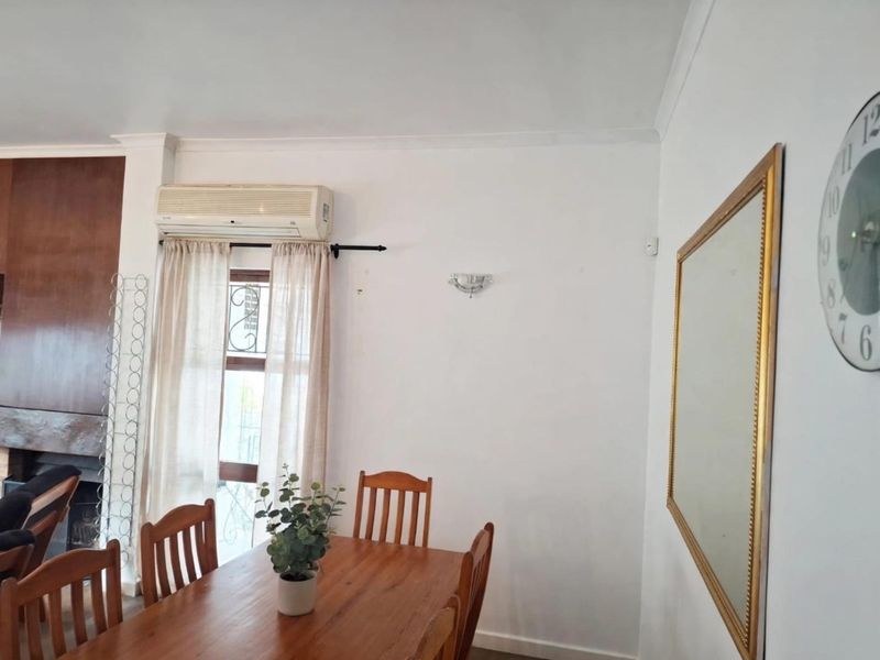 A dining area featuring a wall-mounted air conditioning unit, decorative wall sconce, and coving, providing a functional space for meals.