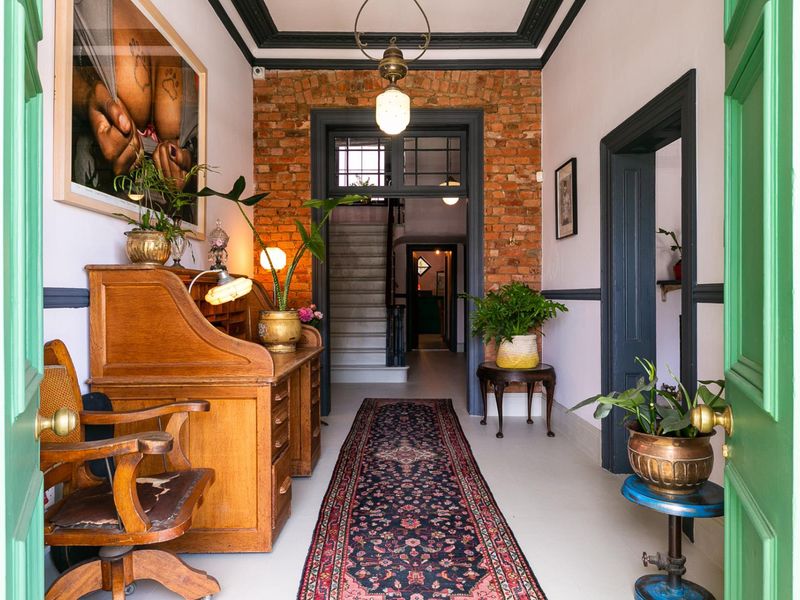 A characterful entrance hallway featuring exposed brickwork, decorative crown molding, and a staircase leading to the upper level.