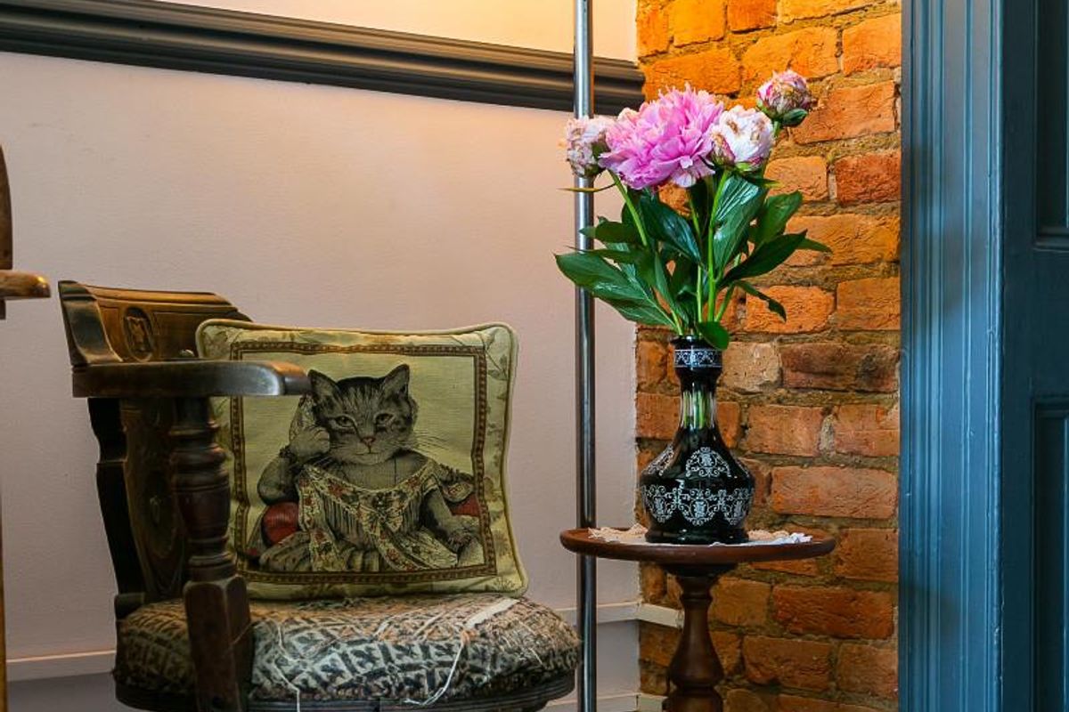A cozy corner featuring an exposed brick wall, decorative chair rail, and painted door frame, creating a warm and character-filled interior space.