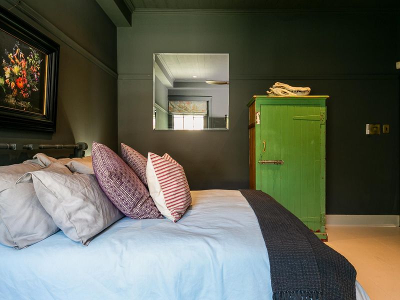 A bedroom featuring dark-painted walls, a built-in wall mirror, and a painted timber ceiling, creating a moody and intimate atmosphere.