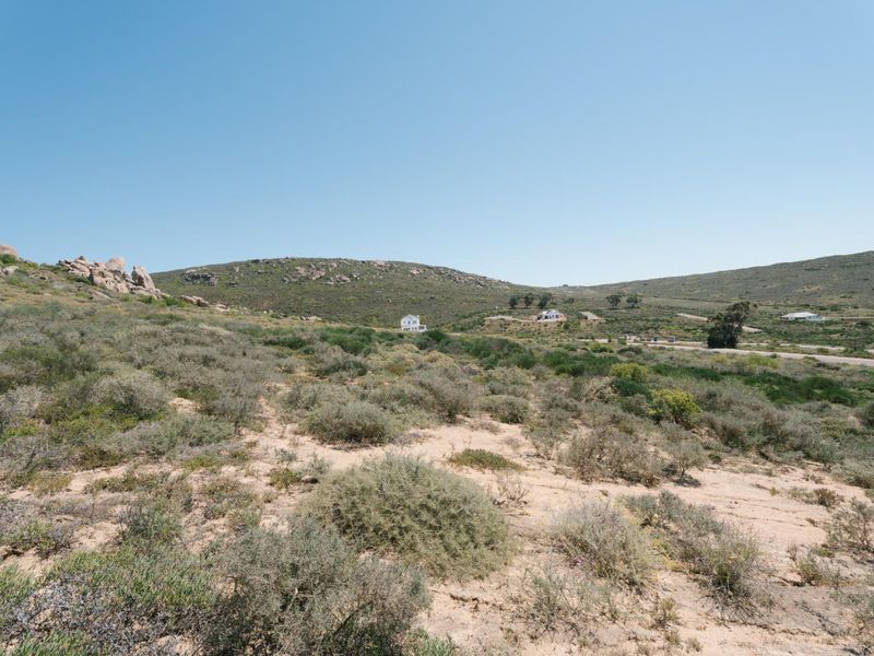 A wide-angle view of the vacant residential land, showcasing the natural landscape, rocky terrain, and surrounding hillside environment.