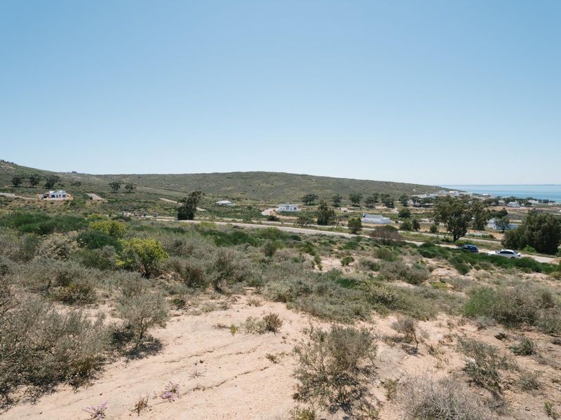 A wide-angle view of the vacant residential land, showcasing the surrounding coastal landscape, natural vegetation, and distant ocean horizon.