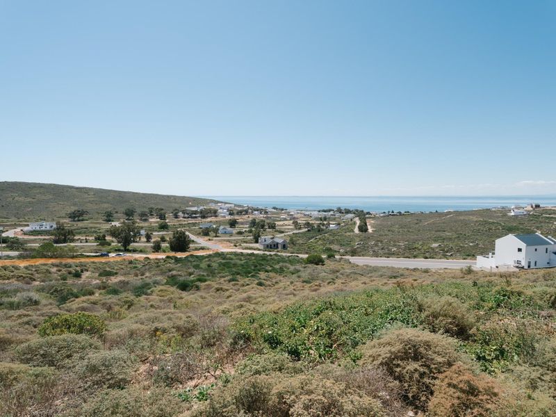An elevated view of the surrounding coastal landscape, featuring natural vegetation, local road infrastructure, and distant ocean views.