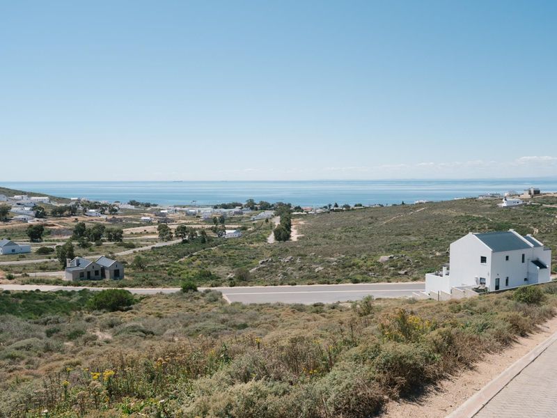 Elevated view overlooking a coastal residential area with paved roads and distant ocean horizon.