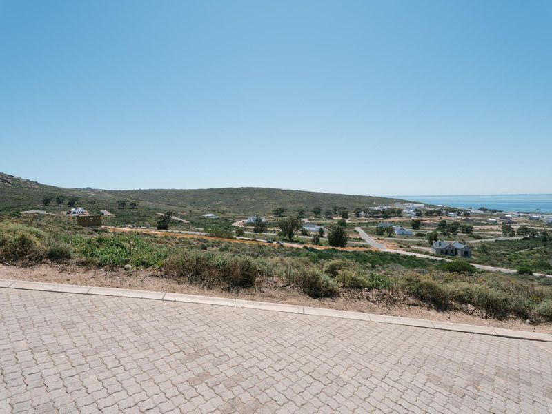 A wide-angle view of the surrounding landscape and coastline from a paved residential street.