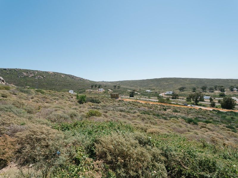 A wide-angle view of the vacant residential land, showcasing the natural sloped terrain and surrounding landscape.