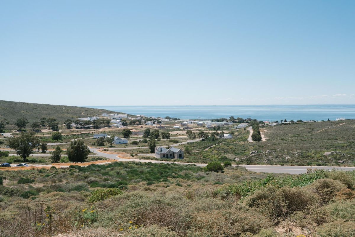 A scenic elevated view overlooking a coastal residential area with natural vegetation and established road infrastructure.