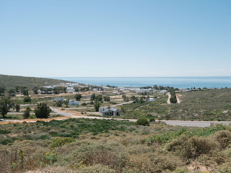A scenic elevated view overlooking a coastal residential area with natural vegetation and established road infrastructure.