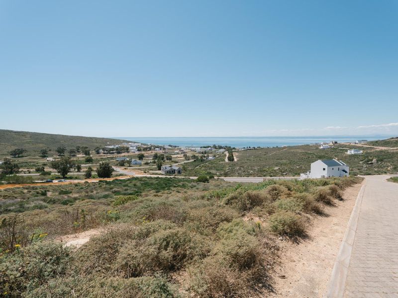 Elevated view overlooking the surrounding coastal landscape and residential area, featuring a paved access road in the foreground.