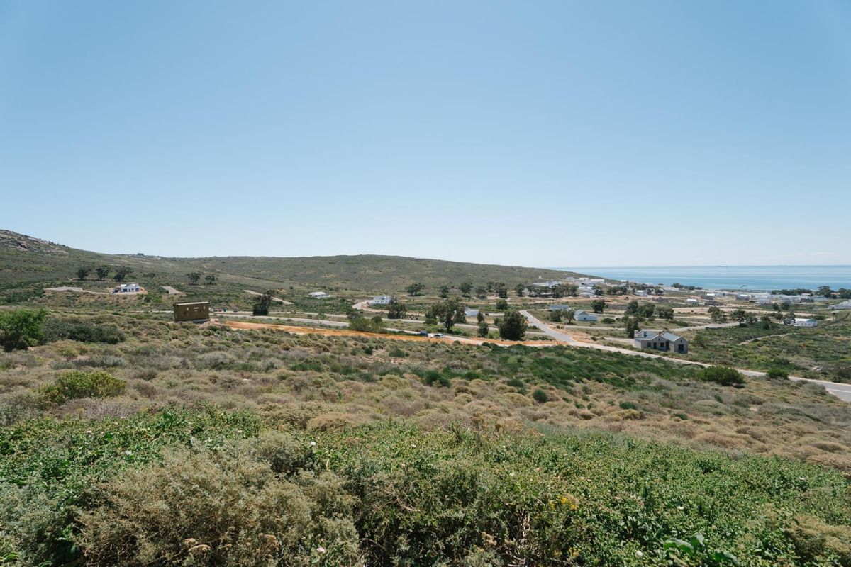 A wide-angle view of the surrounding coastal landscape and residential area, showcasing the natural terrain and proximity to the ocean.