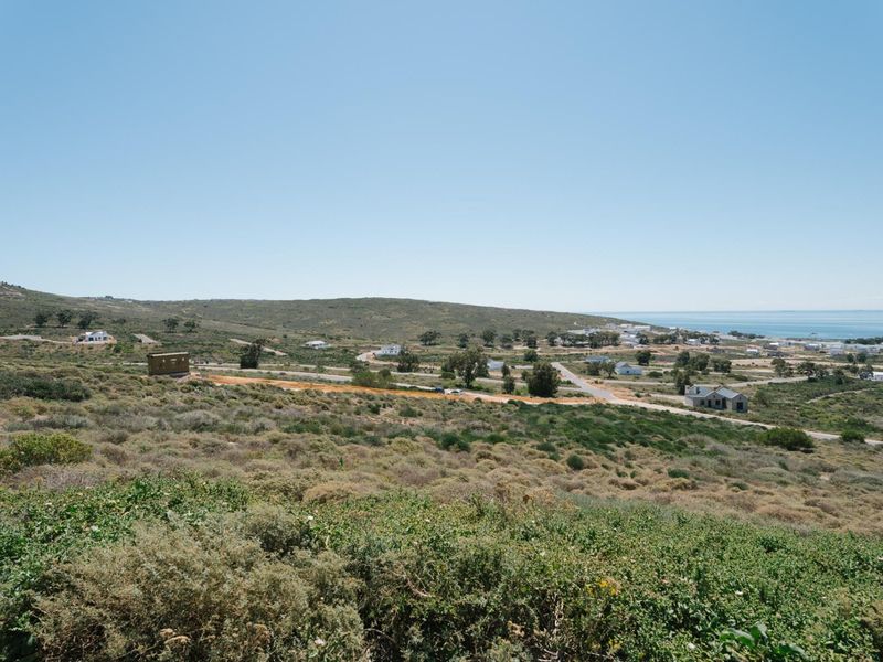 A wide-angle view of the surrounding coastal landscape and residential area, showcasing the natural terrain and proximity to the ocean.