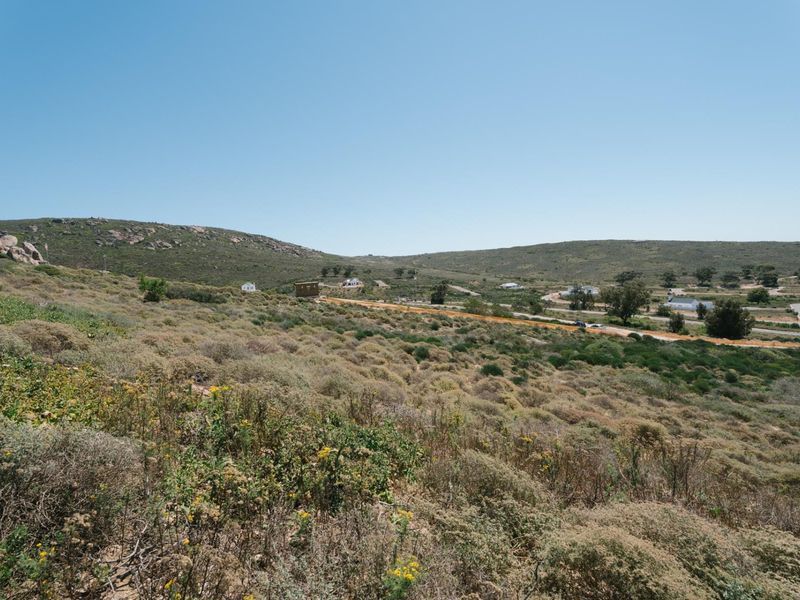 A wide-angle view of the natural landscape and hilly terrain surrounding the vacant residential property.