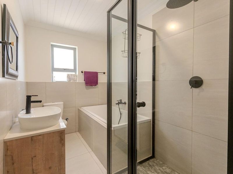 Modern bathroom featuring a sleek vanity with vessel sink, a separate built-in bathtub, and a glass-enclosed shower with contemporary black fixtures.