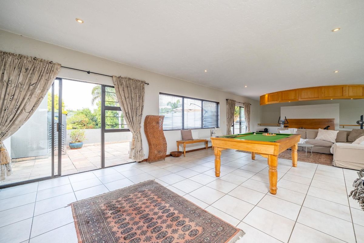 Spacious living area featuring tiled flooring, recessed lighting, and large sliding glass doors providing direct access to an outdoor patio space.