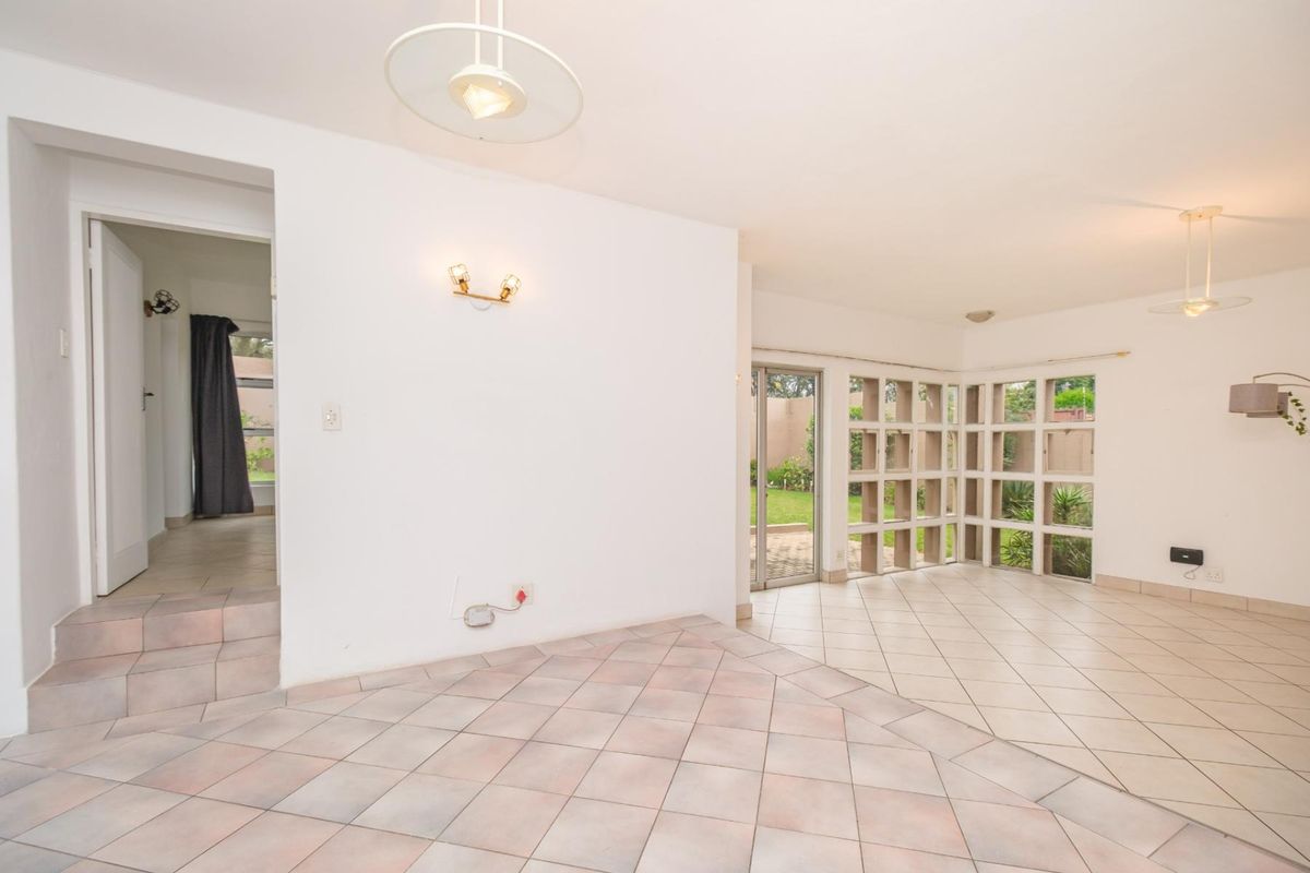 Spacious living area featuring tiled flooring, decorative concrete screen walls, and direct access to the garden through a sliding glass door.
