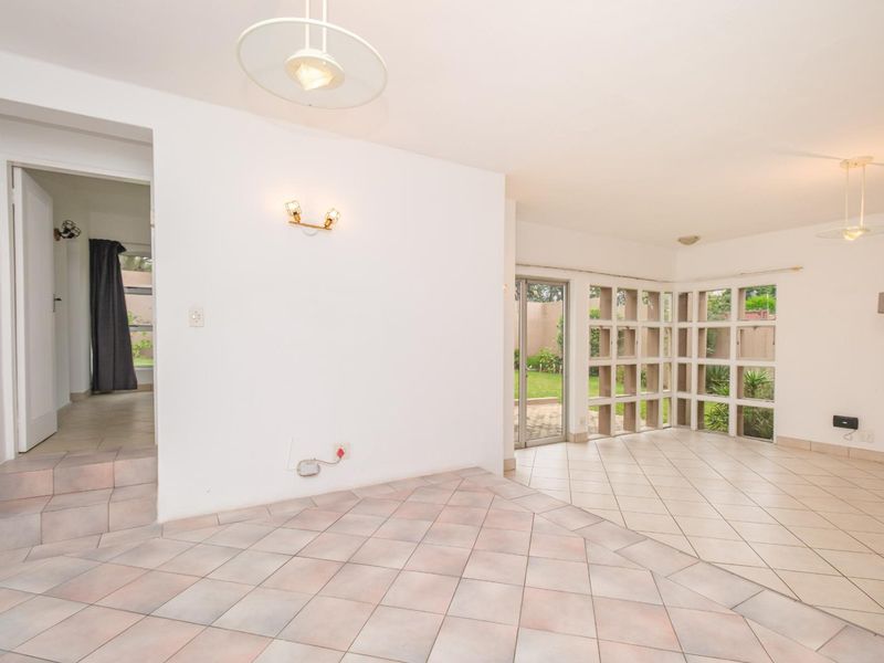 Spacious living area featuring tiled flooring, decorative concrete screen walls, and direct access to the garden through a sliding glass door.