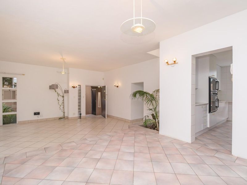 Spacious open-plan living area featuring neutral tiled flooring, integrated kitchen appliances, and a bright, airy layout with direct access to adjacent rooms.