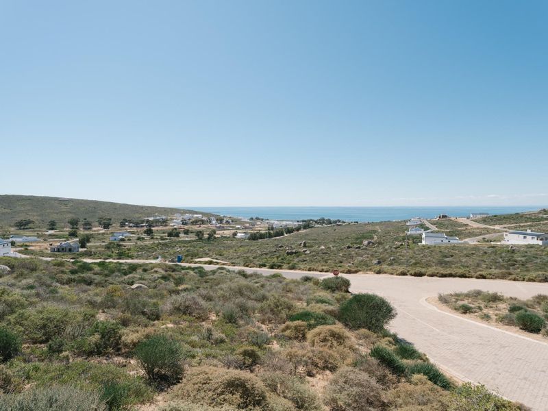 A scenic elevated view of the surrounding coastal landscape, featuring natural vegetation, paved roads, and distant ocean vistas.