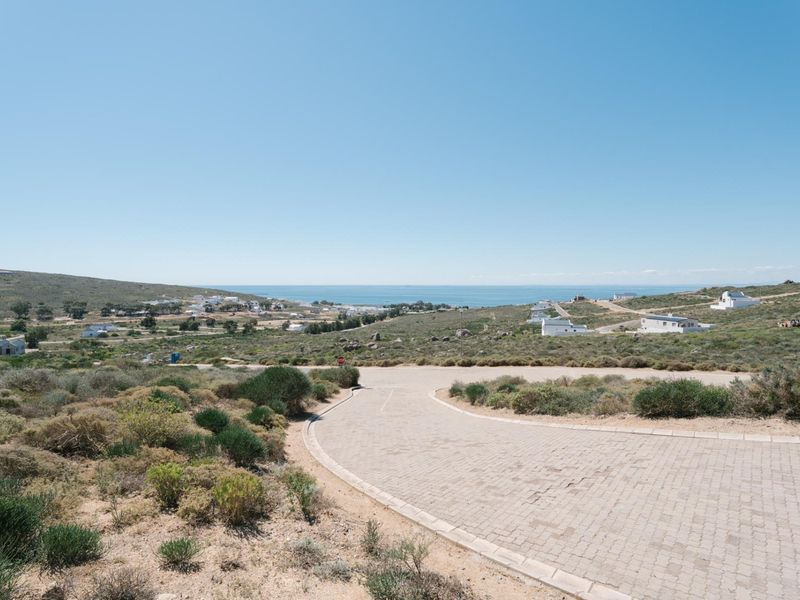 A scenic view of the coastal landscape and surrounding residential area, featuring a paved road leading through the natural terrain.