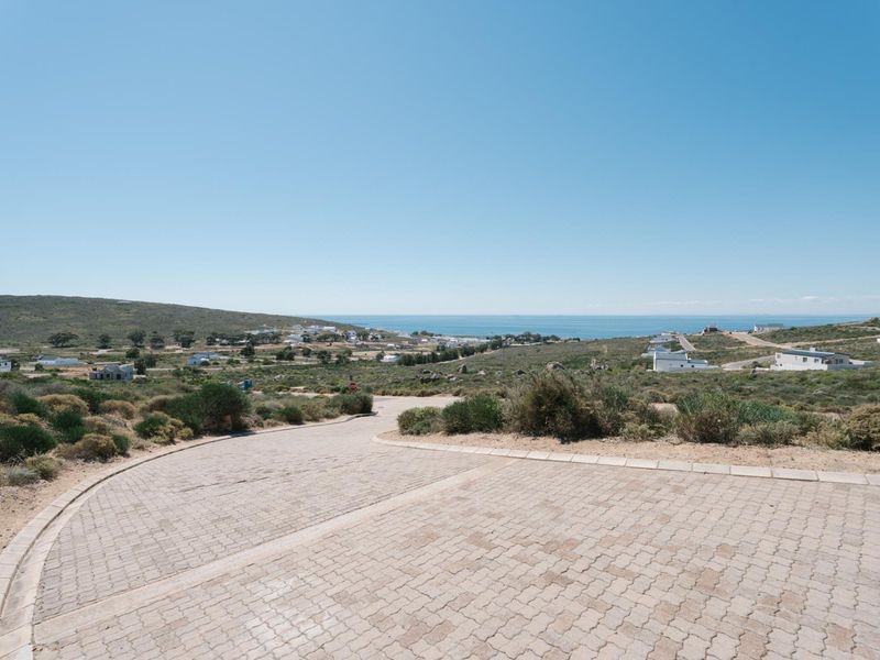 Elevated view overlooking a coastal residential area with a paved driveway in the foreground.