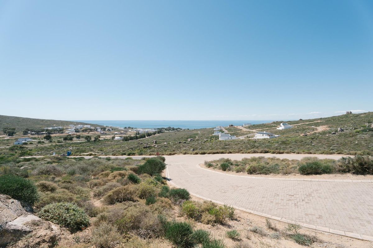 A scenic elevated view of the coastal landscape and surrounding residential area, featuring a paved access road in the foreground.