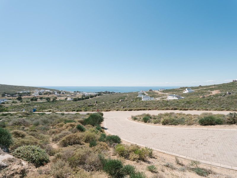 A scenic elevated view of the coastal landscape and surrounding residential area, featuring a paved access road in the foreground.