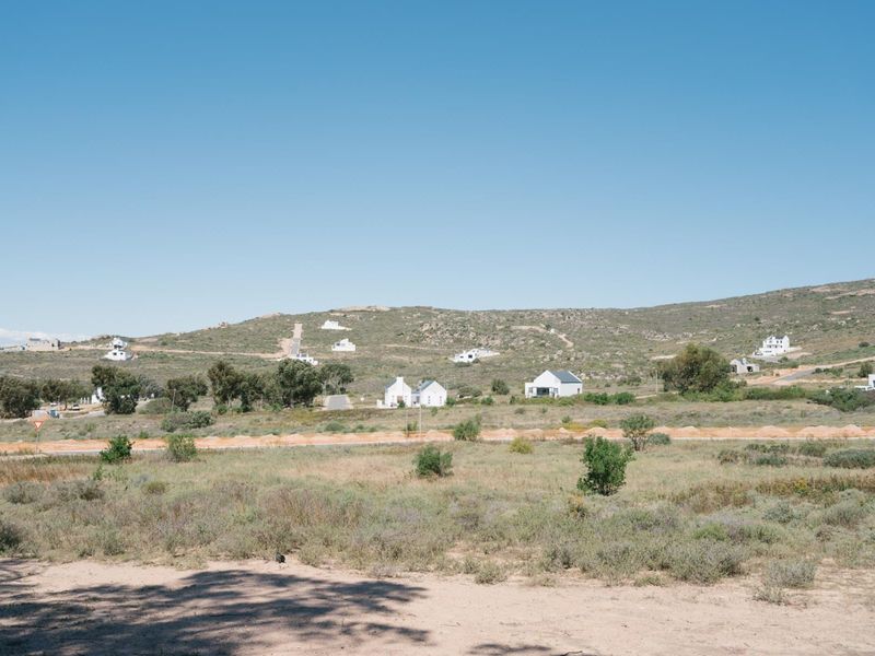 A wide-angle view of the vacant residential land, showcasing the surrounding natural landscape and distant hillside properties.