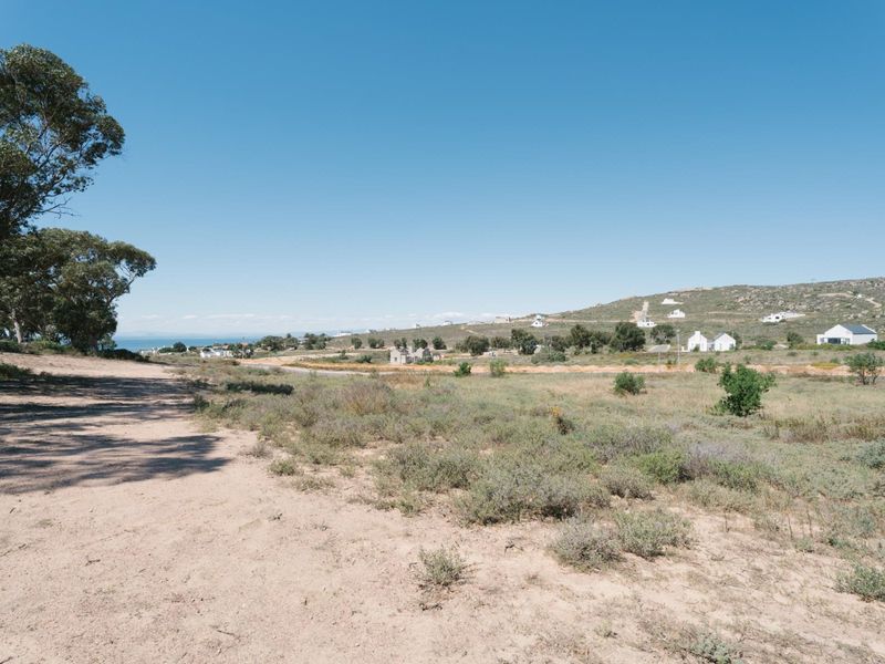 A wide-angle view of the vacant residential land, showcasing the natural landscape, surrounding terrain, and distant coastal horizon.