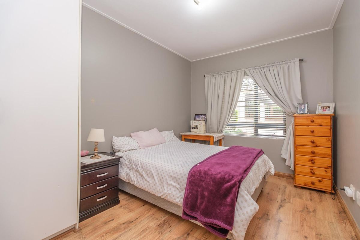 A functional bedroom featuring laminate flooring, a built-in wardrobe, and window treatments, offering a neutral base for personalization.