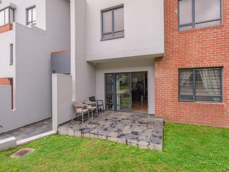 A ground floor patio featuring slate tiling, accessible via a sliding glass door, set against a modern brick and plastered exterior facade.
