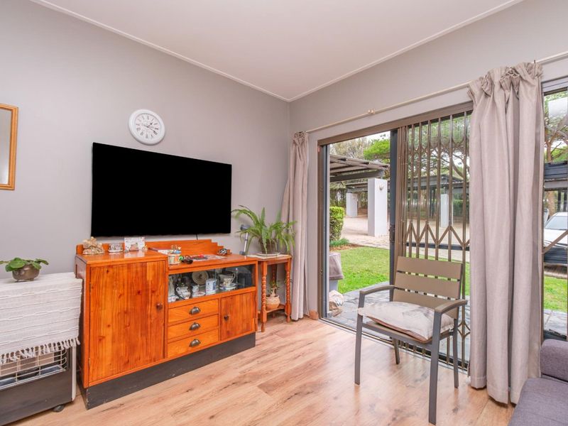 Living room featuring laminate flooring and a sliding glass door with a security gate, providing direct access to the garden area.
