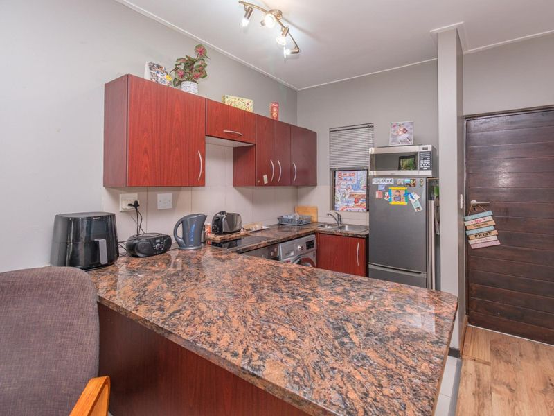 Compact kitchen featuring granite countertops, laminate cabinetry, and integrated appliances, providing a functional workspace with efficient layout.