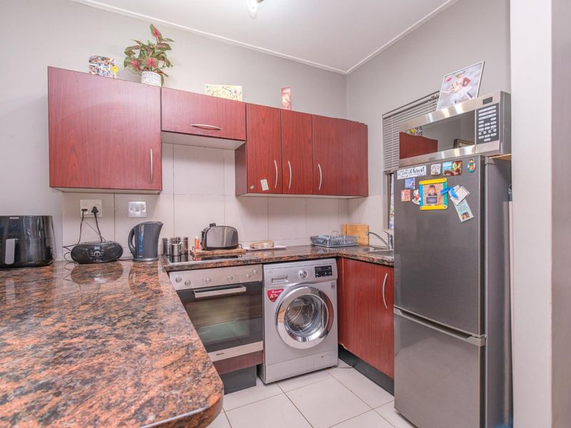 Compact kitchen featuring granite countertops, built-in cabinetry, integrated oven, and a dedicated space for a washing machine.
