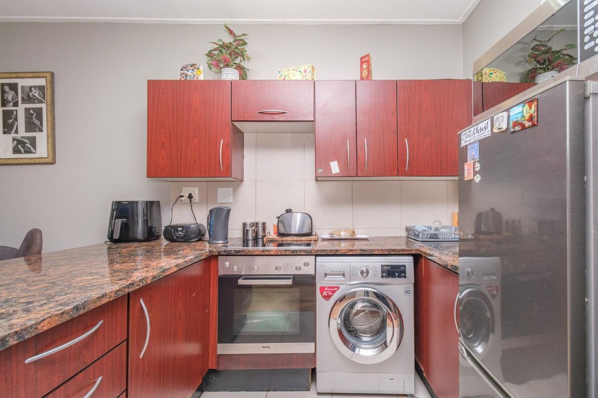 Compact kitchen featuring dark wood-look cabinetry, granite countertops, a built-in oven, and an integrated washing machine.