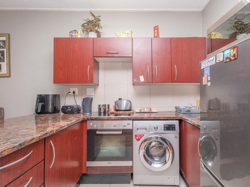 Compact kitchen featuring dark wood-look cabinetry, granite countertops, a built-in oven, and an integrated washing machine.