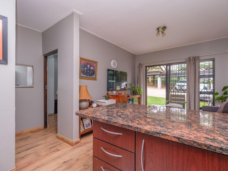 Open plan living area featuring a granite-topped kitchen island, laminate flooring, and sliding glass doors providing access to the exterior.