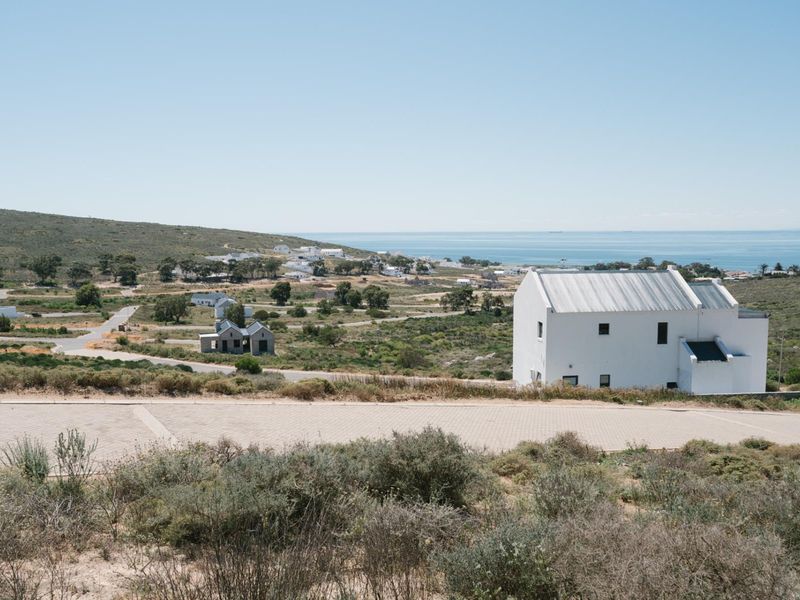 An elevated view of a residential development site featuring paved roads and coastal landscape views.