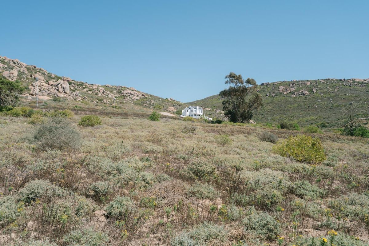 A wide-angle view of the natural, undeveloped residential land featuring rocky hills and native vegetation.