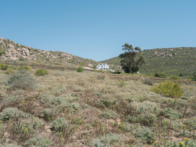 A wide-angle view of the natural, undeveloped residential land featuring rocky hills and native vegetation.