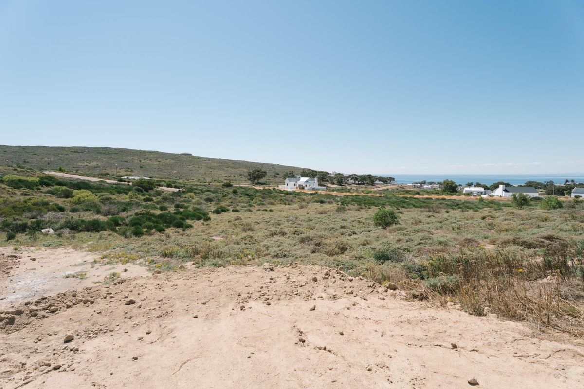 A wide-angle view of the vacant residential land featuring natural coastal vegetation and distant ocean views.