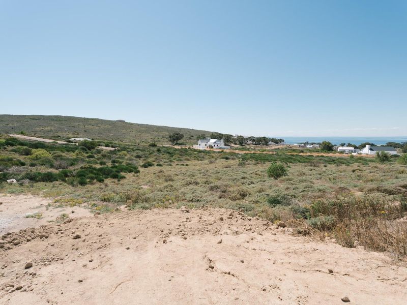 A wide-angle view of the vacant residential land featuring natural coastal vegetation and distant ocean views.