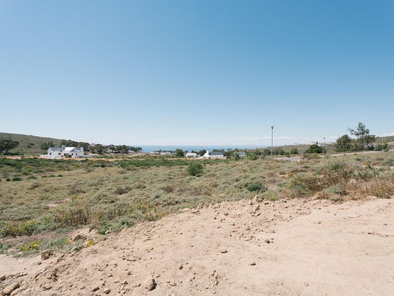 A wide-angle view of the vacant residential land, showcasing the natural coastal landscape and surrounding neighbourhood.