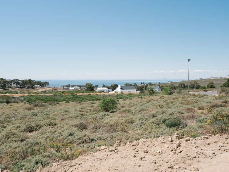 A wide-angle view of the vacant residential land featuring natural coastal vegetation and distant ocean views.