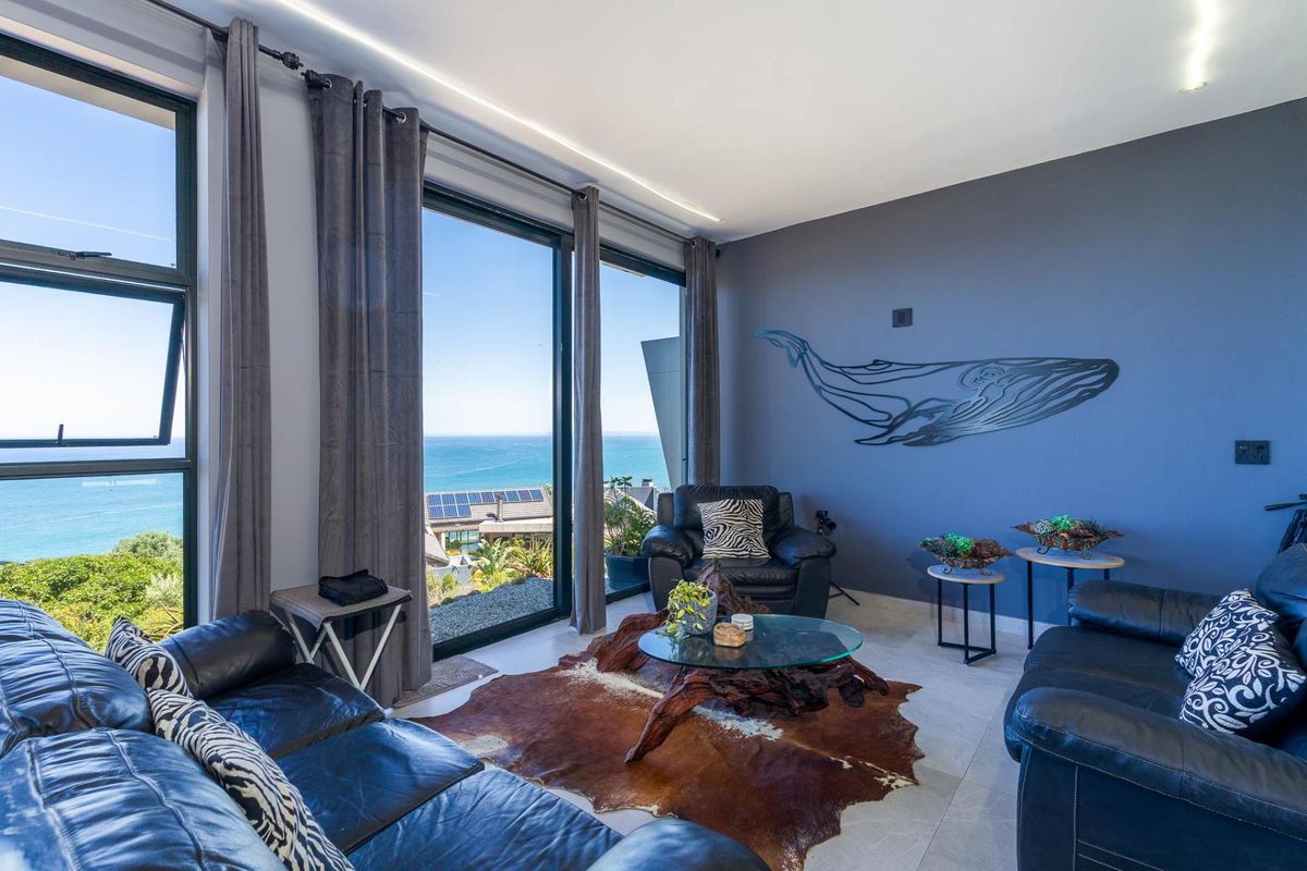 A bright living room featuring expansive floor-to-ceiling windows that offer panoramic ocean views and provide abundant natural light.
