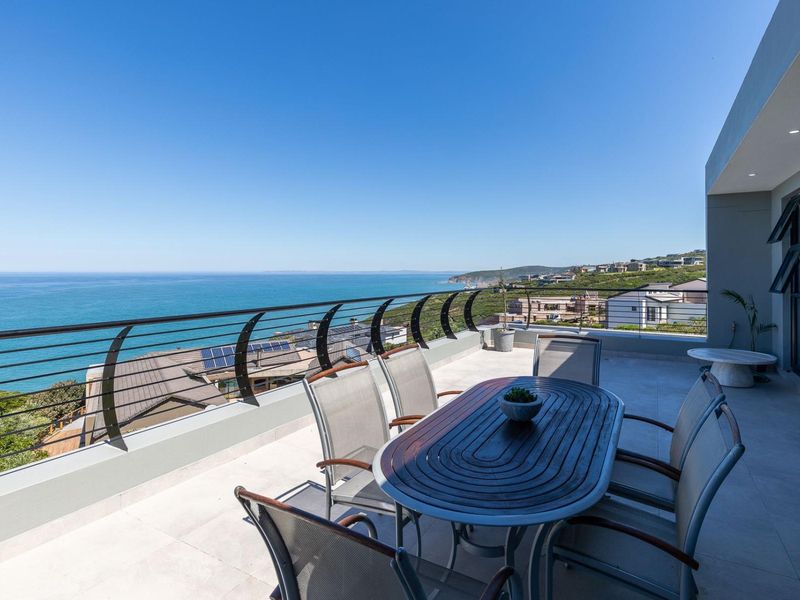 Spacious balcony featuring tiled flooring, a modern metal balustrade, and expansive ocean views, perfect for outdoor dining and relaxation.